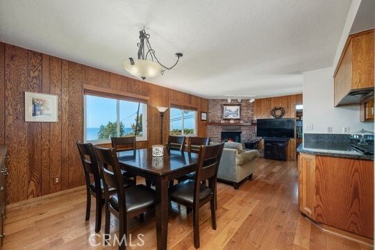 6741 Monero Dr, Rancho Palos Verdes, CA 90275 - dining room featuring light wood finished floors, wooden walls, and a fireplace