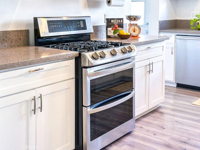 1927 W 84th Pl, Los Angeles, CA 90047 - kitchen featuring stainless steel appliances, white cabinetry, light wood finished floors, and light countertops