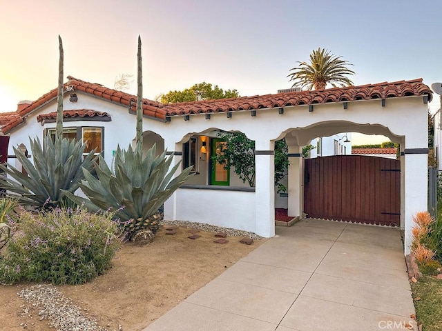 1927 W 84th Pl, Los Angeles, CA 90047 - mediterranean / spanish-style home featuring stucco siding, a tiled roof, and a gate