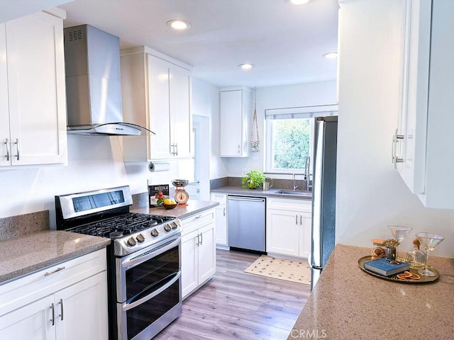 1927 W 84th Pl, Los Angeles, CA 90047 - kitchen with appliances with stainless steel finishes, wall chimney range hood, light wood-style flooring, white cabinetry, and light stone counters