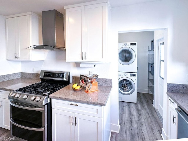1927 W 84th Pl, Los Angeles, CA 90047 - kitchen featuring stainless steel appliances, stacked washer and clothes dryer, wall chimney exhaust hood, and light wood-style floors