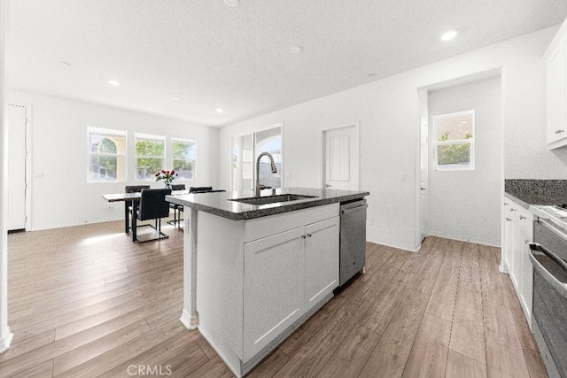 16075 Osprey Ave, Chino, CA 91708 - kitchen featuring appliances with stainless steel finishes, a sink, light wood finished floors, white cabinets, and a center island with sink