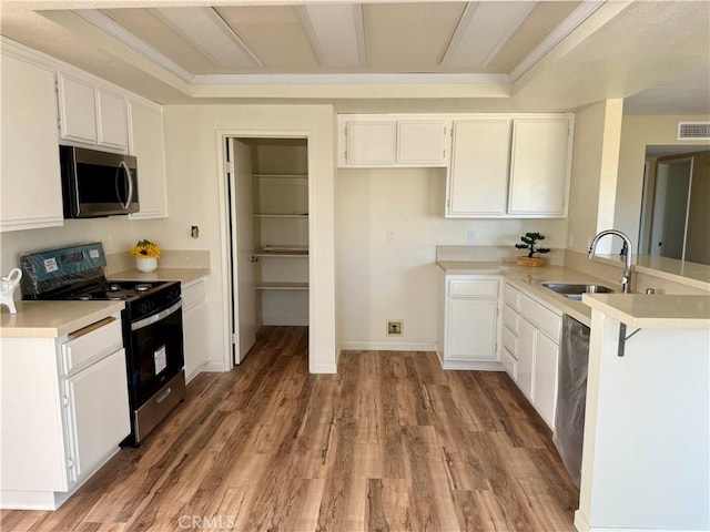 15620 Smoke Tree St, Hesperia, CA 92345 - kitchen featuring appliances with stainless steel finishes, a peninsula, light countertops, white cabinetry, and light wood-type flooring