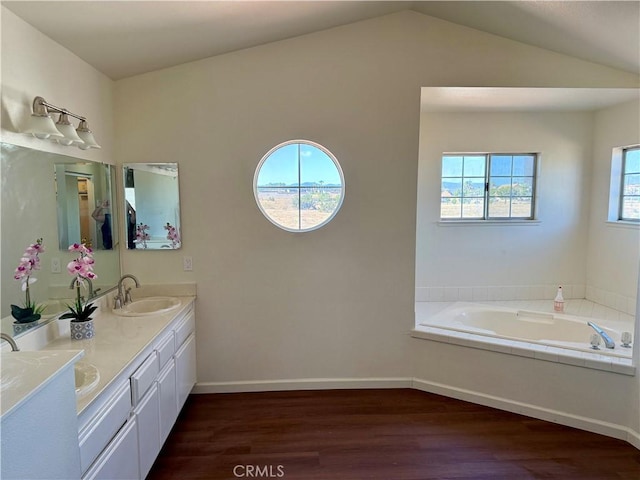 15620 Smoke Tree St, Hesperia, CA 92345 - bathroom featuring wood finished floors, double vanity, vaulted ceiling, a bath, and baseboards