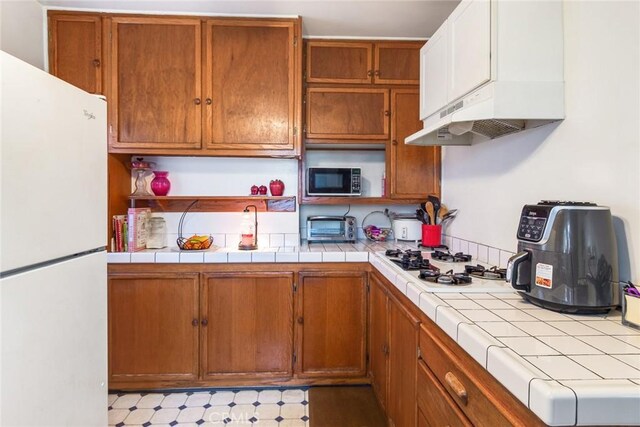 946 W 9th St, Corona, CA 92882 - kitchen with white appliances, under cabinet range hood, and brown cabinets