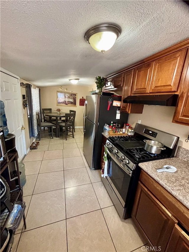 16739 Upland, Fontana, CA 92335 - kitchen with appliances with stainless steel finishes, under cabinet range hood, light tile patterned floors, brown cabinets, and a textured ceiling