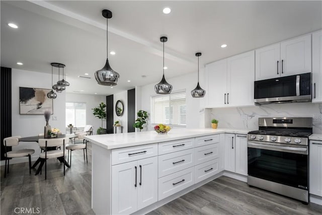 10806 S St Andrews Pl, Los Angeles, CA 90047 - kitchen with stainless steel appliances, a peninsula, white cabinets, decorative backsplash, and wood finished floors