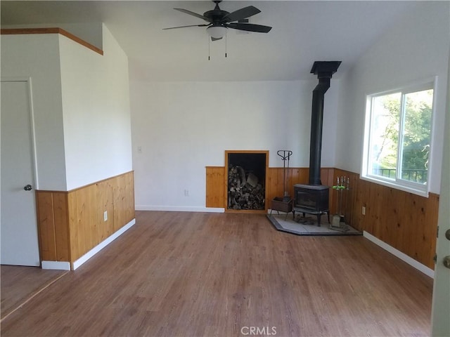 587 Spring Dr, Cedarpines Park, CA 92322 - unfurnished living room with a wood stove, wainscoting, wood finished floors, ceiling fan, and wooden walls