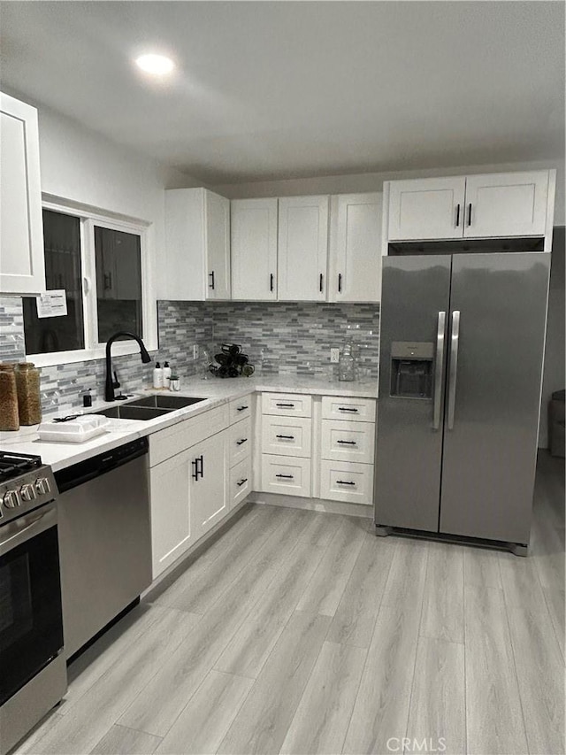 8916 Mettler Ave, Los Angeles, CA 90003 - kitchen featuring stainless steel appliances, a sink, white cabinets, light countertops, and backsplash