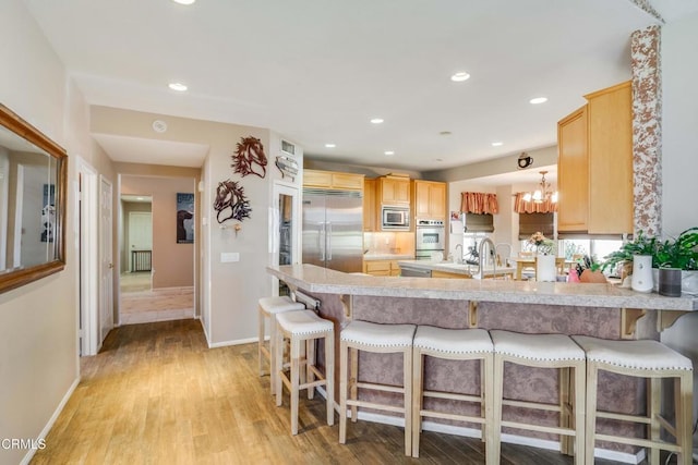 35135 Caprock Rd, Santa Clarita, CA 91390 - kitchen with built in appliances, light brown cabinets, a peninsula, light wood-style floors, and light countertops
