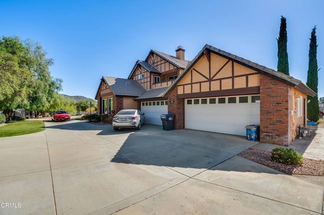 35135 Caprock Rd, Santa Clarita, CA 91390 - tudor-style house with an attached garage, concrete driveway, a chimney, and brick siding