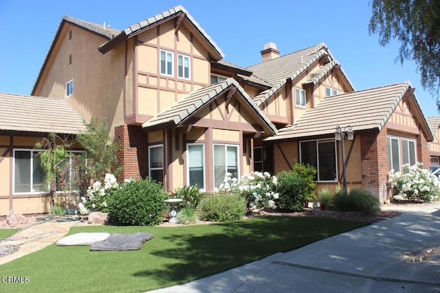 35135 Caprock Rd, Santa Clarita, CA 91390 - tudor-style house with stucco siding, brick siding, a tile roof, and a chimney