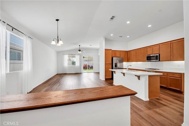 30268 Cherry Opal Ln, Menifee, CA 92584 - kitchen featuring stainless steel appliances, a sink, lofted ceiling, wood finished floors, and brown cabinets