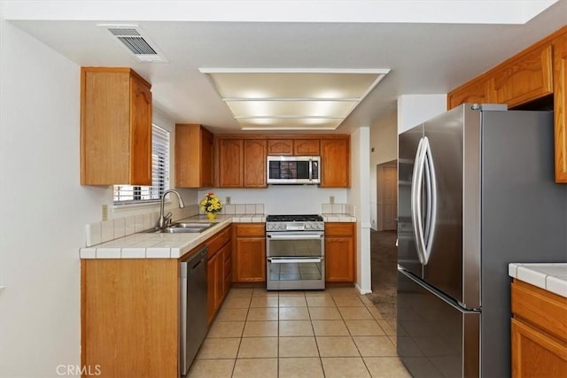 19126 Frances St, Apple Valley, CA 92308 - kitchen with stainless steel appliances, a sink, light tile patterned flooring, tile countertops, and brown cabinets