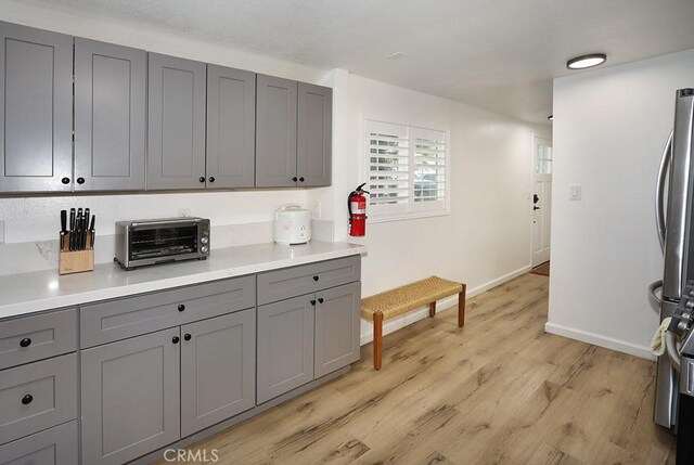 531 W Victoria Ct, Lake Arrowhead, CA 92352 - kitchen with gray cabinetry, light wood-type flooring, baseboards, light countertops, and freestanding refrigerator