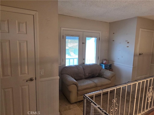 17352 Rob Roy Cir, Huntington Beach, CA 92647 - living room featuring french doors, a wainscoted wall, a textured ceiling, and light tile patterned flooring