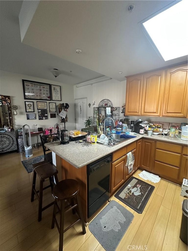 17888 Alburtis Ave Unit B112, Artesia, CA 90701 - kitchen with dishwasher, a sink, a peninsula, light wood-style flooring, and a skylight