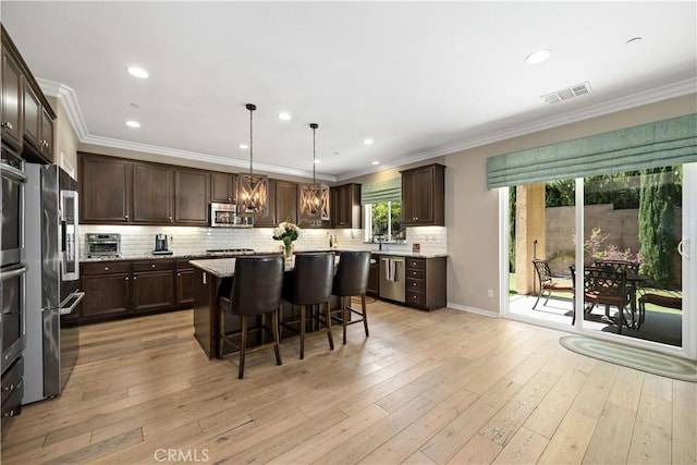 44260 Nighthawk Pass, Temecula, CA 92592 - kitchen featuring stainless steel appliances, dark brown cabinets, a breakfast bar, a center island, and ornamental molding