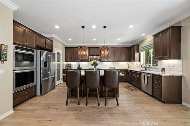 44260 Nighthawk Pass, Temecula, CA 92592 - kitchen with stainless steel appliances, a sink, dark brown cabinetry, a center island, and crown molding