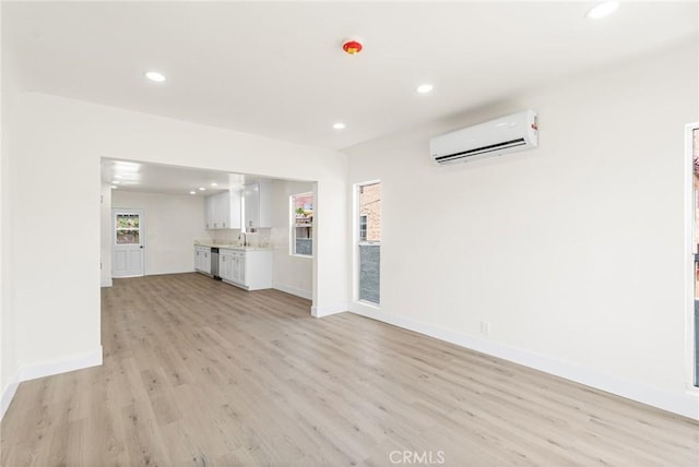 6751 7th Ave, Los Angeles, CA 90043 - unfurnished living room with a wall unit AC, light wood-style floors, recessed lighting, and baseboards