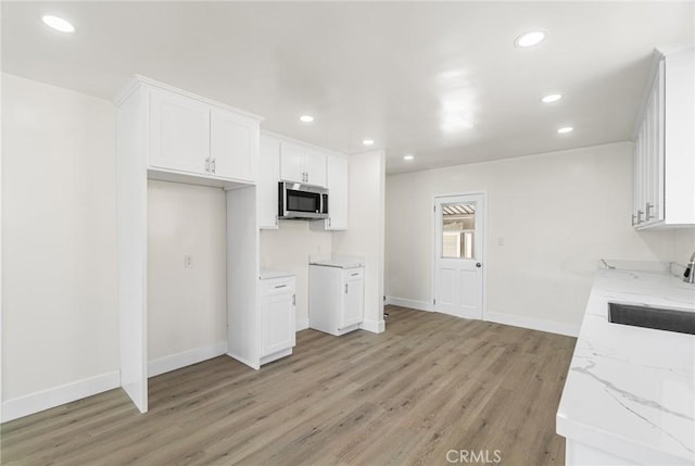 6751 7th Ave, Los Angeles, CA 90043 - kitchen with stainless steel microwave, light stone counters, light wood-type flooring, recessed lighting, and white cabinets