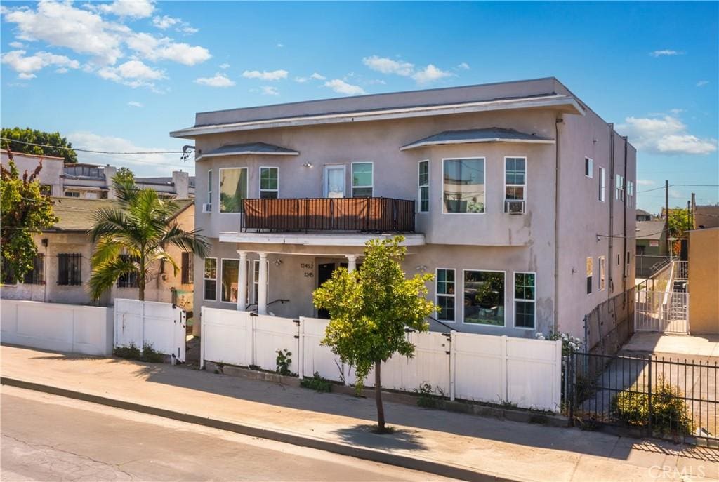 1243 S Kenmore Ave, Los Angeles, CA 90006 - view of front of house featuring a balcony, stucco siding, a gate, and a fenced front yard