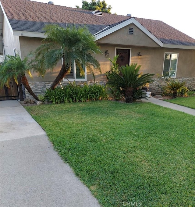 11022 Maple St, Whittier, CA 90601 - view of front facade with stucco siding, a front yard, roof with shingles, and stone siding