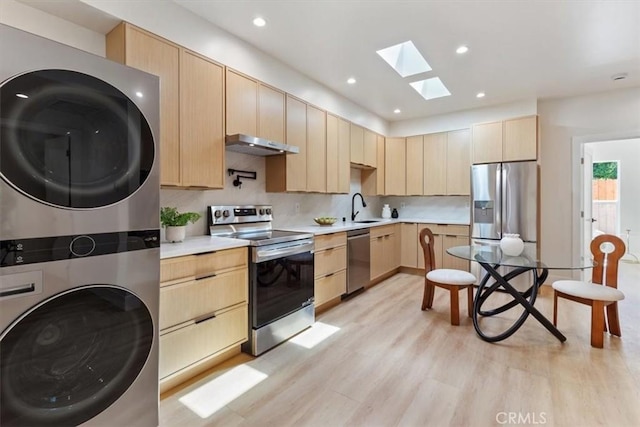 22452 Dolorosa St, Woodland Hills, CA 91367 - kitchen featuring appliances with stainless steel finishes, stacked washer / dryer, light brown cabinetry, a skylight, and a sink
