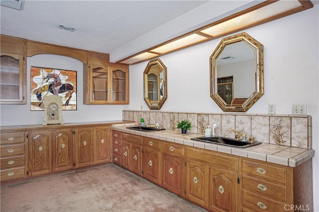 350 Roughrider Rd, La Verne, CA 91750 - kitchen with a sink, brown cabinetry, light carpet, glass insert cabinets, and decorative backsplash