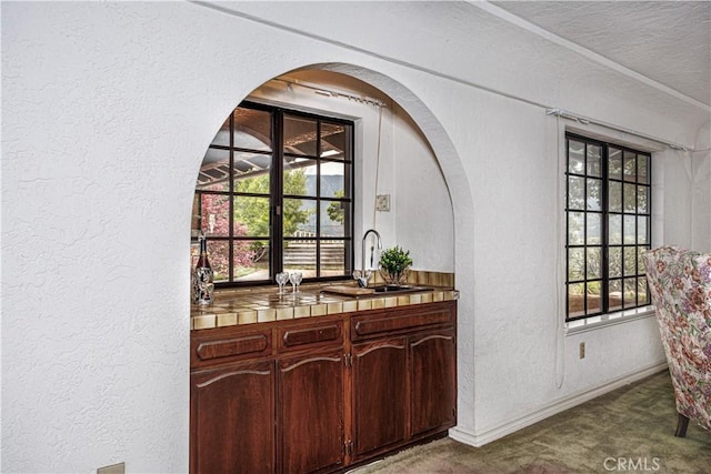 350 Roughrider Rd, La Verne, CA 91750 - bar featuring a textured wall, dark colored carpet, a sink, baseboards, and arched walkways