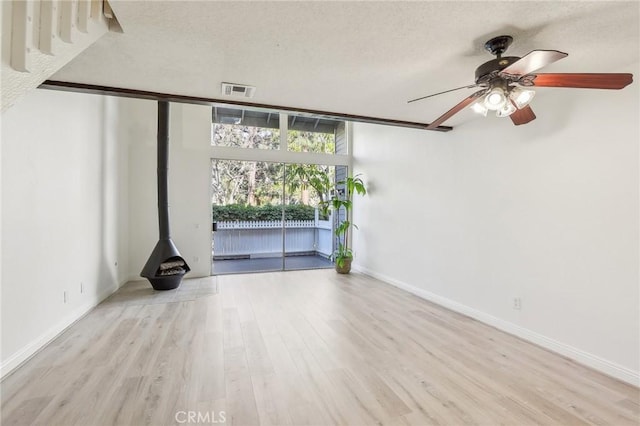 25447 Pine Creek Ln, Wilmington, CA 90744 - unfurnished living room with a textured ceiling, wood finished floors, ceiling fan, baseboards, and a wood stove