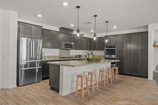 11066 Guffey Ranch Way, Corona, CA 92883 - kitchen with appliances with stainless steel finishes, light wood-style floors, light stone countertops, a breakfast bar, and recessed lighting