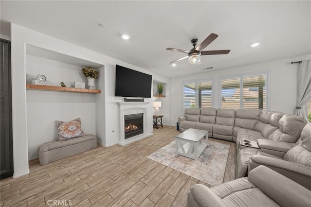 11066 Guffey Ranch Way, Corona, CA 92883 - living room with light wood-style floors, ceiling fan, a lit fireplace, and recessed lighting