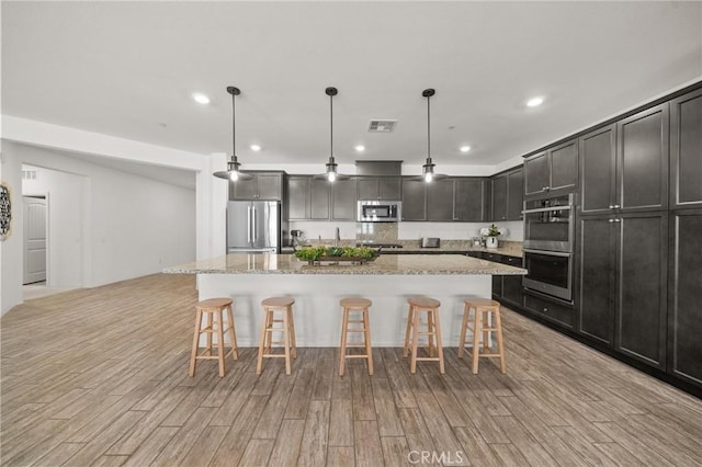11066 Guffey Ranch Way, Corona, CA 92883 - kitchen with stainless steel appliances, light wood-style flooring, a breakfast bar area, and recessed lighting