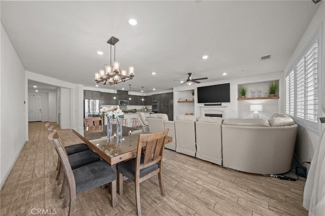 11066 Guffey Ranch Way, Corona, CA 92883 - dining area featuring a fireplace, ceiling fan, a chandelier, light wood-type flooring, and recessed lighting