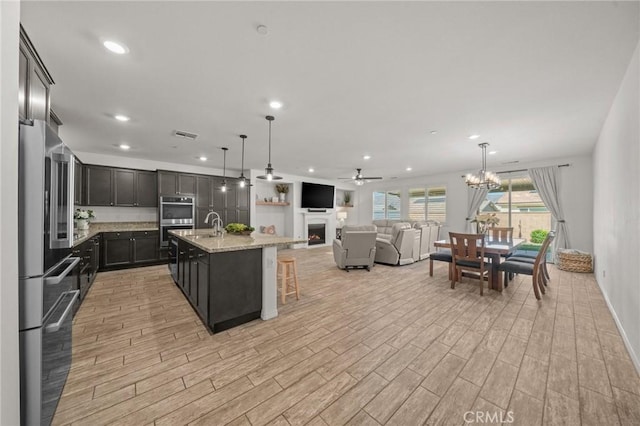 11066 Guffey Ranch Way, Corona, CA 92883 - kitchen with stainless steel appliances, light wood finished floors, a ceiling fan, recessed lighting, and open floor plan