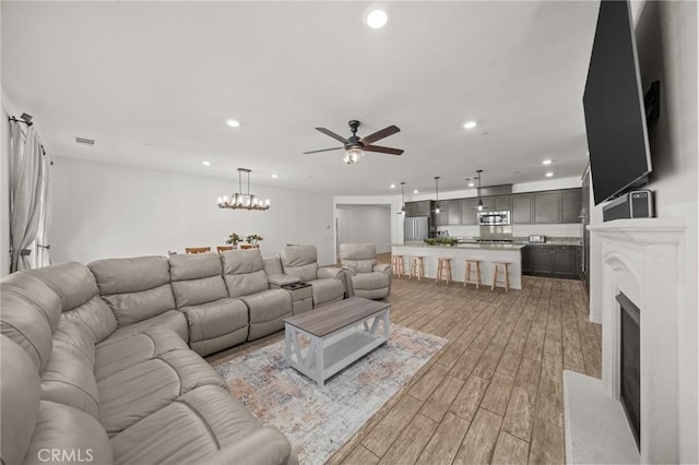 11066 Guffey Ranch Way, Corona, CA 92883 - living area featuring light wood finished floors, recessed lighting, a ceiling fan, a fireplace, and a chandelier