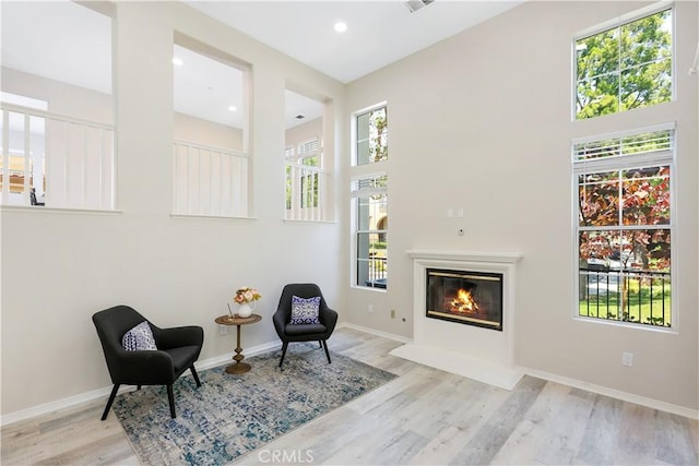 36 Chula Vis Unit 109, Irvine, CA 92602 - sitting room with a glass covered fireplace, wood finished floors, baseboards, a high ceiling, and recessed lighting