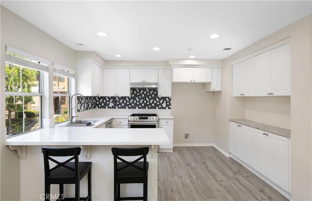 36 Chula Vis Unit 109, Irvine, CA 92602 - kitchen with stainless steel gas range, a sink, a peninsula, light wood-style floors, and white cabinets