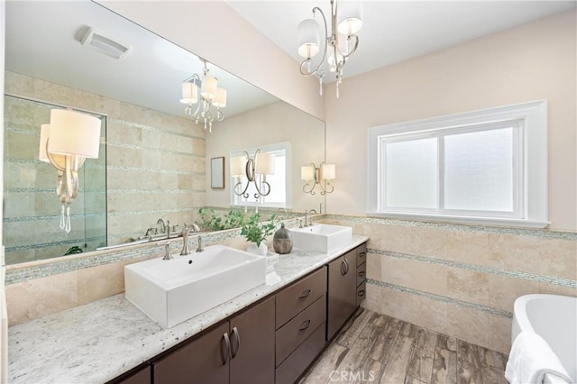 1202 Duke Ln, Walnut, CA 91789 - bathroom featuring tile walls, a chandelier, a freestanding bath, double vanity, and wood finished floors