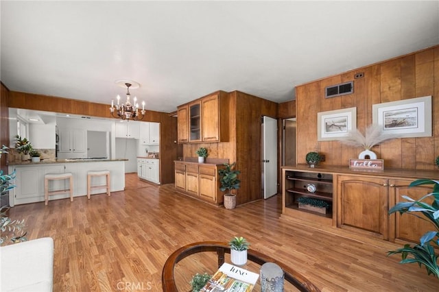 1424 E Vine Ave, West Covina, CA 91791 - living room with a chandelier, light wood-type flooring, and wooden walls