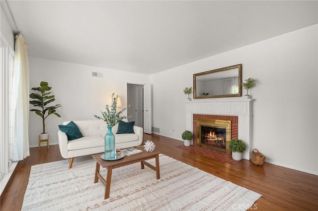 1424 E Vine Ave, West Covina, CA 91791 - living area featuring wood finished floors, a brick fireplace, and baseboards