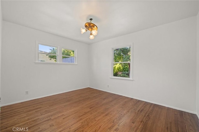 1424 E Vine Ave, West Covina, CA 91791 - unfurnished room with healthy amount of natural light, wood finished floors, baseboards, and a chandelier
