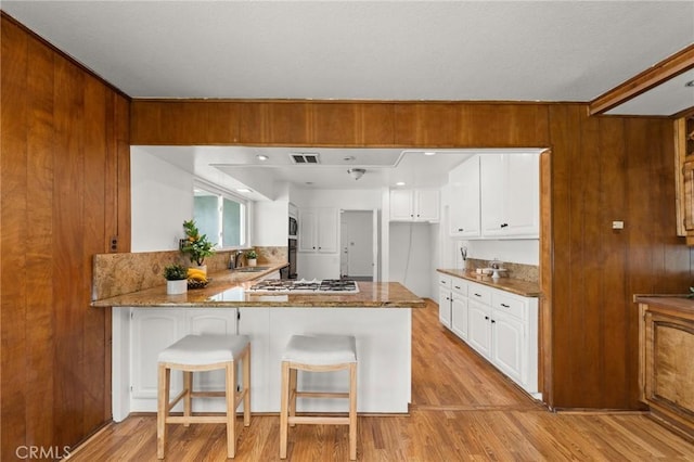 1424 E Vine Ave, West Covina, CA 91791 - kitchen with a sink, white gas cooktop, a peninsula, white cabinets, and light wood finished floors