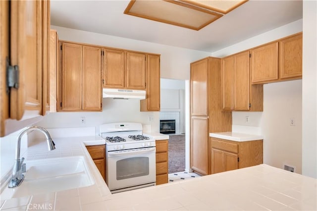 26057 Crestmont Cir, Menifee, CA 92586 - kitchen featuring white gas stove, under cabinet range hood, tile counters, a peninsula, and a glass covered fireplace