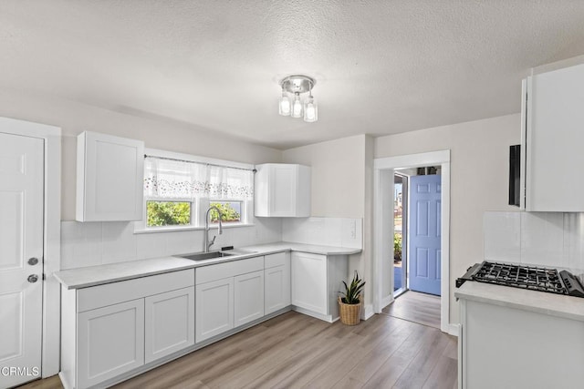 618 S C St, Oxnard, CA 93030 - kitchen featuring a sink, tasteful backsplash, white cabinetry, light countertops, and a textured ceiling