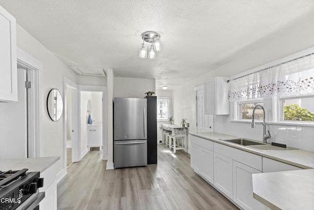 618 S C St, Oxnard, CA 93030 - kitchen with freestanding refrigerator, a sink, white cabinetry, light countertops, and light wood-style floors
