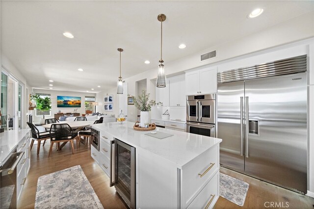 18976 Rockinghorse Ln, Huntington Beach, CA 92648 - kitchen featuring built in appliances, beverage cooler, white cabinets, recessed lighting, and open floor plan