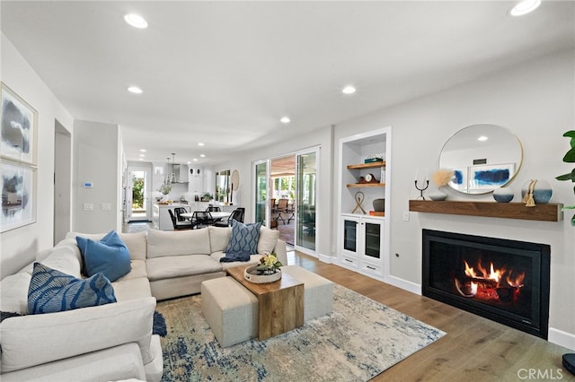 18976 Rockinghorse Ln, Huntington Beach, CA 92648 - living area with recessed lighting, built in shelves, wood finished floors, a warm lit fireplace, and baseboards