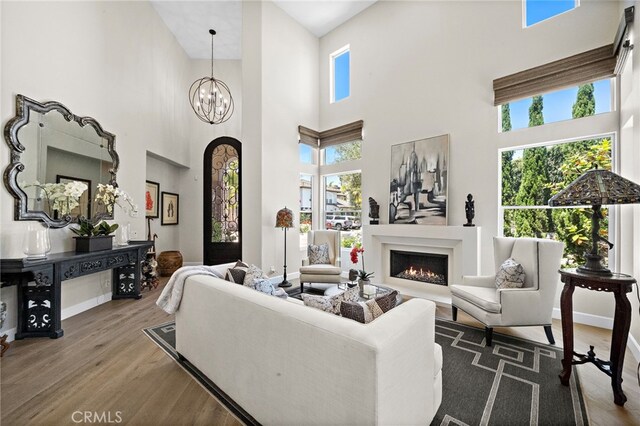 18976 Rockinghorse Ln, Huntington Beach, CA 92648 - living area with a high ceiling, wood finished floors, a warm lit fireplace, a chandelier, and baseboards